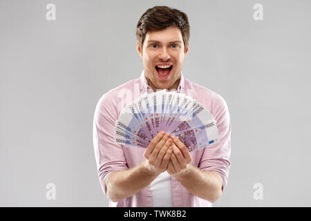 Heureux jeune homme avec le ventilateur de l'argent euro Banque D'Images