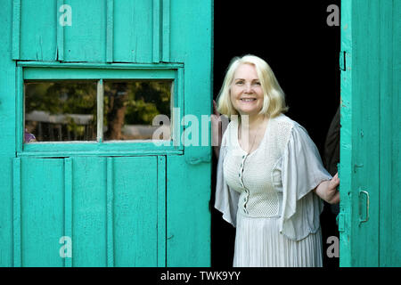 Personnes âgées femme blonde en tenue d'ouverture accueil porte d'entrée. Banque D'Images