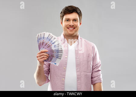 Smiling Young man with fan de euro argent plus de Gray Banque D'Images