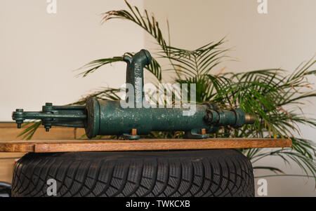 Ancien, vintage, style rétro, la pompe à eau manuelle Vassen sur pneu de voiture et l'arrière-plan de l'usine Banque D'Images