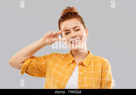 Smiling red haired woman montrant la paix Banque D'Images