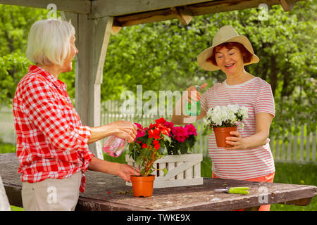 Mesdames sentiment bon. De belles dames de se sentir bien tout en parlant et l'arrosage des plantes en pots Banque D'Images