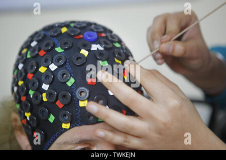 Bangalore, Karnataka, Inde. 13 Décembre, 2018. 13 Dec 2018 - Bangalore, Inde.Un technicien met un couvre-chef avec les sondes pour récupérer les signaux du cerveau.Pendant le test scientifique quand le chant du mot 'AUM' est en cours ; les différentes sondes placées autour de la tête la captation de signaux qui sont traitées par un algorithme informatique. Ces essais menés à l'NIMHANS (Institut National de la santé mentale et de Neuro Sciences, Bengaluru) conclure qu'en raison de la vibration sonore créé pendant la phase 'AUM' chant l'esprit atteint un état profond de relaxation. (Crédit Image : © Subhash Sha Banque D'Images