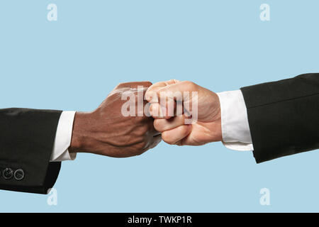 Salutations amis signer ou de désaccord. Deux hommes competion dans Arm wrestling isolé sur fond studio bleu. Concept de Standoff, soutien, amitié, des affaires, de la communauté, des relations tendues. Banque D'Images