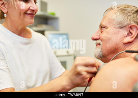 Médecin et patient principal avec stimulation thérapie actuelle pour la circulation du sang et de la douleur Banque D'Images