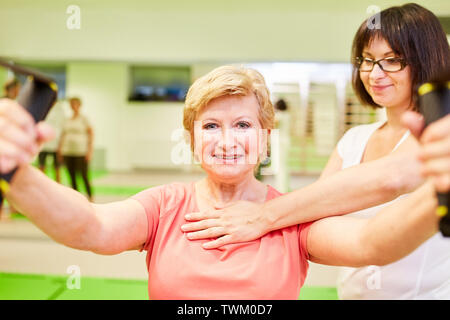 Professeur de fitness ou d'un physiothérapeute aide les femme avec la formation de l'élingue pour le dos Banque D'Images