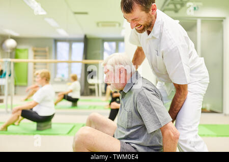 Physiothérapeute senior donne de l'aide pour un exercice de l'arrière dans l'école Cours Reha Banque D'Images