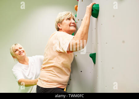 Physiothérapeute senior woman donne l'aide à grimper sur un mur d'escalade Banque D'Images