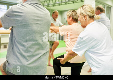 Les personnes âgées donne physiothérapeute aide avec la physiothérapie à la barre de ballet Banque D'Images