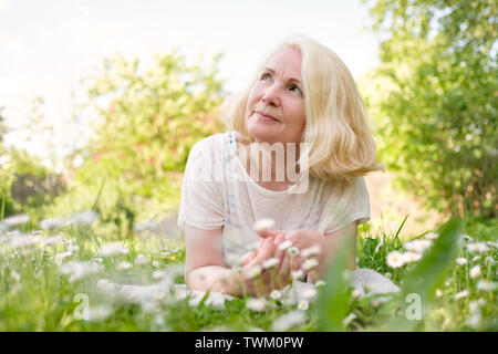 Hauts femme blonde au repos dans l'herbe en été. Banque D'Images