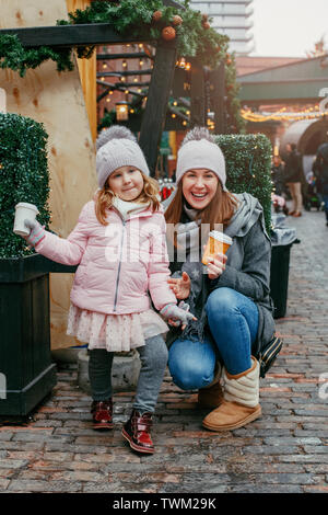 Mère avec enfant girl drinking hot chocolate café au célèbre marché de noël vacances du Nouvel An. Activité de plein air en hiver en famille. Maman et daughte Banque D'Images