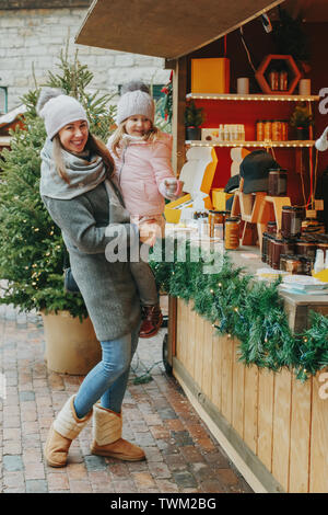 Mère avec enfant fille le choix d'acheter des cadeaux au marché de Noël et la célébration de la nouvelle année. Activité de plein air en hiver en famille. Mère et fille sp Banque D'Images