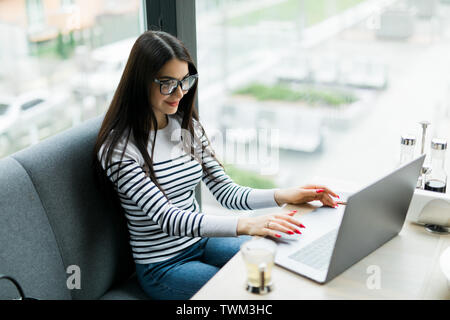 Belle femme de race blanche à rêver de quelque chose alors qu'il était assis avec les net-réserve en café-bar moderne, jeune femme charmante pensée freelancer Banque D'Images