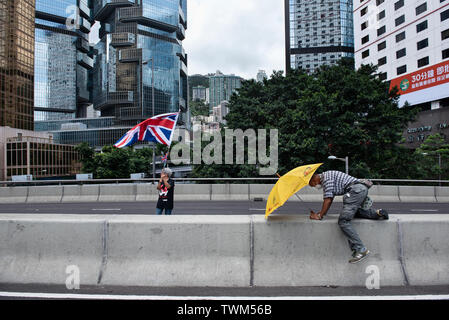 Les vagues un manifestant le Royaume-Uni de Grande-Bretagne et d'Irlande du Nord tandis qu'un autre drapeau est titulaire d'un parapluie jaune, symbole de la circulation, tandis que les routes ont été bloquées. Malgré le chef de la carrie Lam a tenté d'atténuer les tensions en acceptant de suspendre le controversé projet de loi sur l'extradition, des groupes d'étudiants et de l'union a continuer la protestation contre le gouvernement de Hong Kong. Les manifestants ont demandé le retrait de la controversée LOI SUR L'extradition, la libération et la non-poursuite des gens arrêtés en raison de la cause, de savoir si une force excessive Banque D'Images