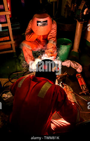 Soudeur et son assistant fabriquer dans un atelier de tuyauterie avec porter un équipement de protection complet Banque D'Images