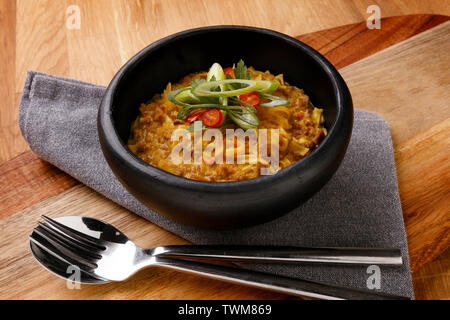 Délicieux bol de chow mein et garnir tourné sur une planche en bois avec une serviette et des couverts. Banque D'Images