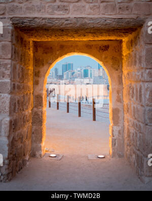 Un encadrement de porte en pierre du château avec vue sur les toits de Bahreïn où les anciens moderne répond aux Banque D'Images