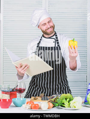 Chef barbu homme à la cuisson des aliments. Guy lire livre de recettes. Concept d'arts culinaires. Apprendre l'homme recette. Améliorer les compétences de cuisson. Guide de cuisson ultime pour les débutants. Livre des recettes de famille. Selon recette. Banque D'Images