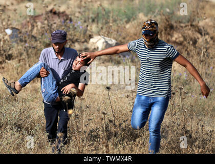 La bande de Gaza. 21 Juin, 2019. Des manifestants palestiniens portent un garçon blessé lors d'affrontements avec les troupes israéliennes sur la frontière Gaza-Israel, à l'est de al-Bureij camp de réfugiés au centre de la bande de Gaza, le 21 juin 2019. Au moins 81 Palestiniens ont été blessés vendredi après-midi au cours d'affrontements entre manifestants palestiniens et soldats israéliens à l'est de la bande de Gaza, près de la frontière avec Israël, a déclaré que les infirmiers. Credit : Yasser Qudih/Xinhua/Alamy Live News Banque D'Images