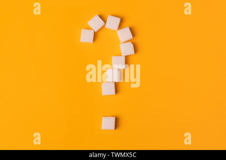 Cubes de sucre blanc en forme de point d'interrogation sur fond orange. Vue d'en haut. Pour régimes unhealty sweet addiction concept Banque D'Images