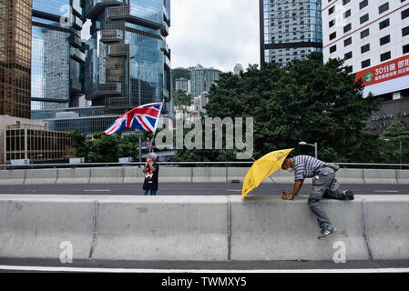 Les vagues un manifestant le Royaume-Uni de Grande-Bretagne et d'Irlande du Nord tandis qu'un autre drapeau est titulaire d'un parapluie jaune, symbole de la circulation, tandis que les routes ont été bloquées. Malgré le chef de la carrie Lam a tenté d'atténuer les tensions en acceptant de suspendre le controversé projet de loi sur l'extradition, des groupes d'étudiants et de l'union a continuer la protestation contre le gouvernement de Hong Kong. Les manifestants ont demandé le retrait de la controversée LOI SUR L'extradition, la libération et la non-poursuite des gens arrêtés en raison de la cause, de savoir si une force excessive Banque D'Images