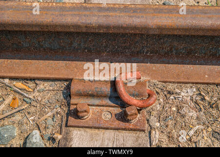 Rusty ancienne gare ferroviaire piste boulonnée avec une plaque et vis à une traverse en bois Banque D'Images