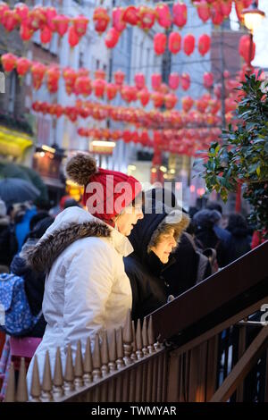 Deux convives féminines en hiver utilisent un menu de restaurant dans le quartier chinois de Londres avec des lanternes chinoises en arrière-plan Banque D'Images