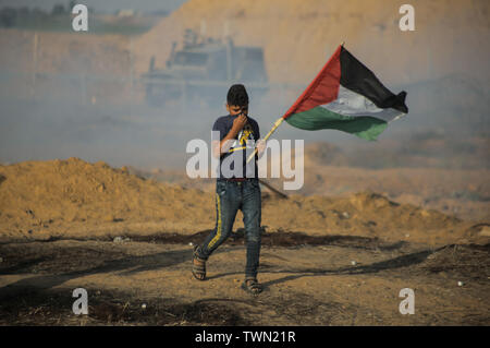 Un manifestant palestinien s'enfuit avec un drapeau de fumée de gaz lacrymogènes tirés sur eux pendant les affrontements.palestiniens se sont affrontés avec les forces israéliennes au cours d'une manifestation appelant à la levée du blocus israélien de Gaza et exigeante pour le droit de retourner dans leur patrie, à l'Israel-Gaza clôture frontalière dans le sud de la bande de Gaza. Banque D'Images