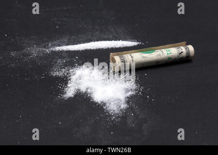 Poudre de cocaïne dans les lignes et une facture d'un dollar. Stupéfiants, une pile de drogues sur fond noir. Banque D'Images
