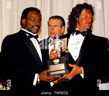 23 janvier 1988 - Washington, District of Columbia, États-Unis - Chicago Bears Walter Payton running back (34), à gauche, et l'actrice, scénariste, producteur et Sylvester Stallone, droite, tenez le Timmie Award, tenez le trophée à être présenté à la défensive s'attaquer le Tchad Hennings de l'United States Air Force Academy, le Collège 1987 Poseur de l'année. Le prix est présenté dans le mémoire de Knute Rockne par le Washington, DC Touchdown Club à Washington, DC Le 23 janvier 1988. Au centre est l'ancien entraîneur-chef Redskins de Washington George Allen (crédit Image : © Arnie Sachs/CNP via ZUM Banque D'Images