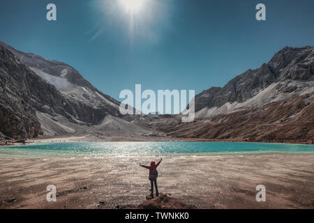 Lever les mains en l'air avec touristiques lac turquoise et de montagnes sur le pic. La réserve naturelle de Yading Banque D'Images