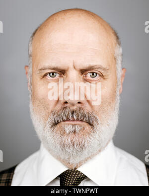 Serious mature businessman standing et la pose, il est à regarder la caméra avec attitude confiante Banque D'Images