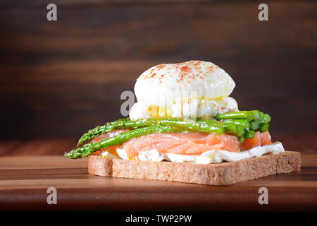 Œufs pochés avec asperges frits, fromage à la crème, le saumon et les épices sur un toast. Œufs pochés avec fuite.Petit-déjeuner français sain concept Banque D'Images