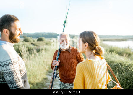 Jeune homme et femme avec des grand-père vêtus de pulls prévues un bon temps ensemble pendant que la pêche dans la matinée Banque D'Images
