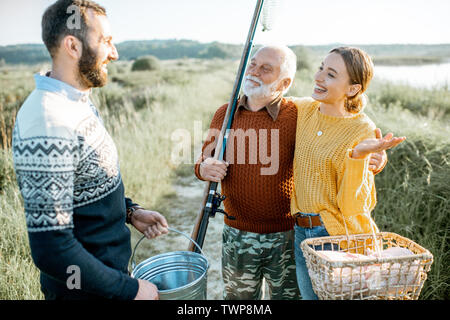 Jeune homme et femme avec des grand-père vêtus de pulls prévues un bon temps ensemble pendant que la pêche dans la matinée Banque D'Images