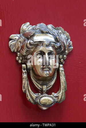 Poignée de porte en bronze décoratifs sous la forme d'une belle tête de la femme sur une porte peinte en jaune. Malte. Banque D'Images