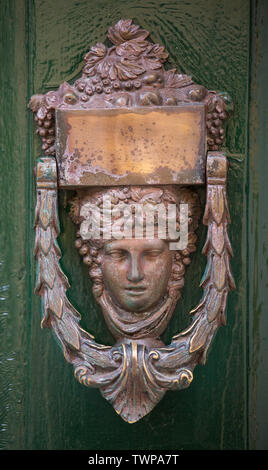 Poignée de porte en bronze décoratifs sous la forme d'une belle tête de la femme sur une porte peinte en jaune. Malte. Banque D'Images