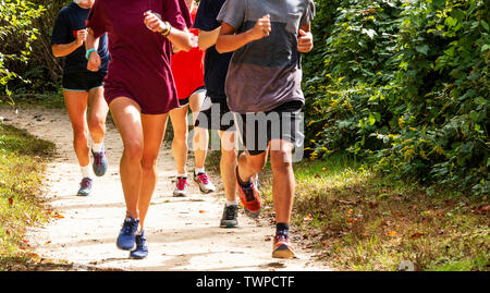 Un groupe de coureurs de l'école de formation sont ensemble sur un chemin de terre sous le soleil d'après-midi, courir vers la caméra. Banque D'Images