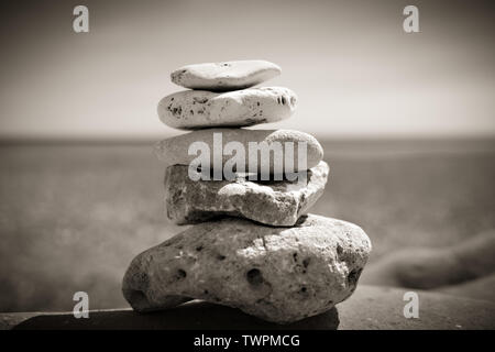 Cairn de pierre sur la plage à l'océan en noir et blanc Banque D'Images