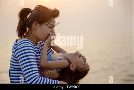 Beau moment avec maman et enfant jouer et câlin avec coucher du soleil lumière chaude. L'amour en famille Banque D'Images