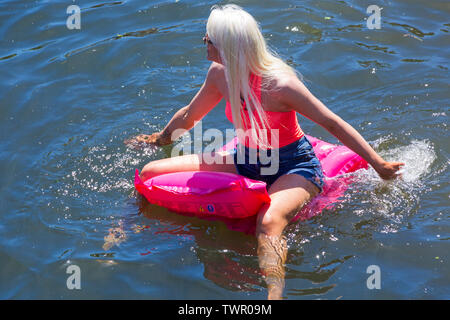 Iford, Dorset, UK. 22 juin 2019. Un temps magnifique, ensoleillé et chaud, toujours pour Dorset Canot Journée avec des centaines de jeux gonflables, des dériveurs, artisanat, conseils formant une flottille, de mettre les voiles de l'IFORD pont rivière Stour de Tuckton bridge. L'événement a commencé en 2014 comme un petit peu de plaisir, mais est maintenant devenu un événement annuel recueillant des fonds pour des organismes de bienfaisance et fonceur plus grand chaque année. Femme rester au frais sur gonflable. Credit : Carolyn Jenkins/Alamy Live News Banque D'Images