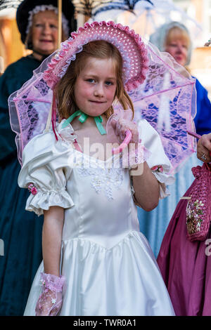 Festival annuel de Broadstairs Dickens. Enfant, fille, 8-10 ans, posant à l'époque victorienne robe blanche et rose bonnet rose avec parasol. Eye-contact. Banque D'Images