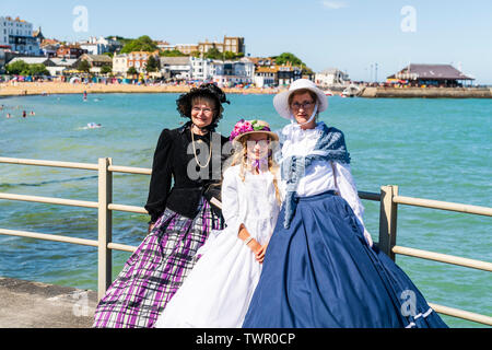 Festival annuel de Broadstairs Dickens. Des gens habillés en costume comme Victoria Dickens Dickens divers caractères. Deux femmes d'un groupe allemand Dickens portant des bonnets, sur la promenade du front de mer le posant avec derrière eux. Enfant, fille, 8-10 ans, fille d'un comité permanent entre eux. Banque D'Images