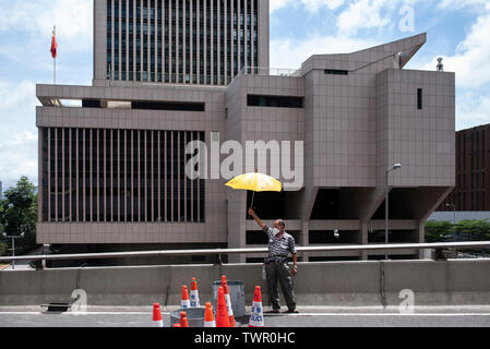 Un manifestant tient un parapluie jaune, un symbole utilisé au cours de la circulation parapluie, près de l'Armée de libération du peuple chinois de Hong Kong Forces bâtiment. Malgré le chef de la carrie Lam a tenté d'atténuer les tensions en acceptant de suspendre le controversé projet de loi sur l'extradition, des groupes d'étudiants et de l'union a continuer la protestation contre le gouvernement de Hong Kong. Les manifestants ont demandé le retrait de la controversée LOI SUR L'extradition, la libération et la non-poursuite des gens arrêtés en raison de la cause, de savoir si une force excessive a été utilisée par la police le 1 juin Banque D'Images