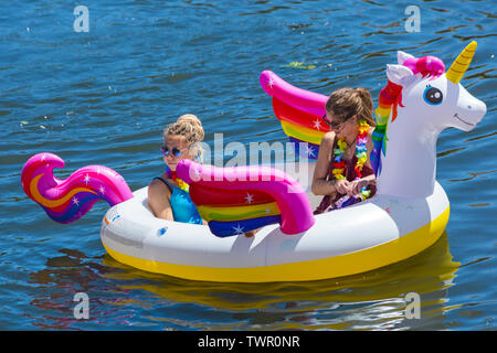 Iford, Dorset, UK. 22 juin 2019. Un temps magnifique, ensoleillé et chaud, toujours pour Dorset Canot Journée avec des centaines de jeux gonflables, des dériveurs, artisanat, conseils formant une flottille, de mettre les voiles de l'IFORD pont rivière Stour de Tuckton bridge. L'événement a commencé en 2014 comme un petit peu de plaisir, mais est maintenant devenu un événement annuel recueillant des fonds pour des organismes de bienfaisance et fonceur plus grand chaque année. Les femmes s'amusant sur unicorn gonflable gonflable. Credit : Carolyn Jenkins/Alamy Live News Banque D'Images