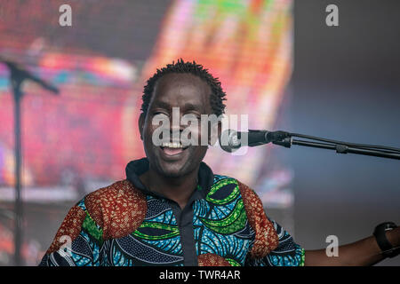 Le chant Gasper Nali divertit la foule à Sefton Park lors de l'événement Liverpool Africa Oye.Gasper Nali est un musicien originaire de Nkhata, originaire du Malawi, sur les rives du lac Malawi. Il joue une guitare basse à une corde avec un bâton et une bouteille de bière vide, ainsi qu'un tambour de pied de peau de vache. Banque D'Images