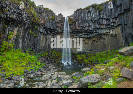 L'exposition longue capture d'attraction touristique emblématique cascade Svartifoss dans le parc national de Skaftafell, entouré de formations de roche basaltique. Banque D'Images