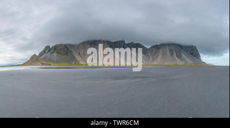 Vue panoramique des montagnes Vestrahorn en Islande pendant la marée basse. Plage de sable noir en face d'une chaîne de montagnes côtières. Banque D'Images