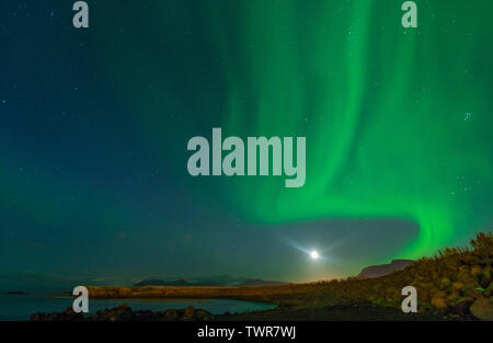 Lune brille avec northern lights afficher en Islande. Ciel coloré dans la nuit, les vagues d'aurores boréales vert bleu la peinture du ciel nocturne. Banque D'Images