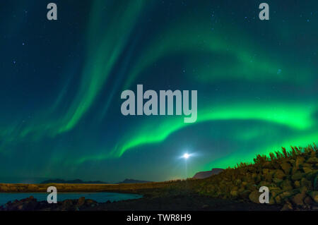 Lune brille avec northern lights afficher en Islande. Ciel coloré dans la nuit, les vagues d'aurores boréales vert bleu la peinture du ciel nocturne. Banque D'Images